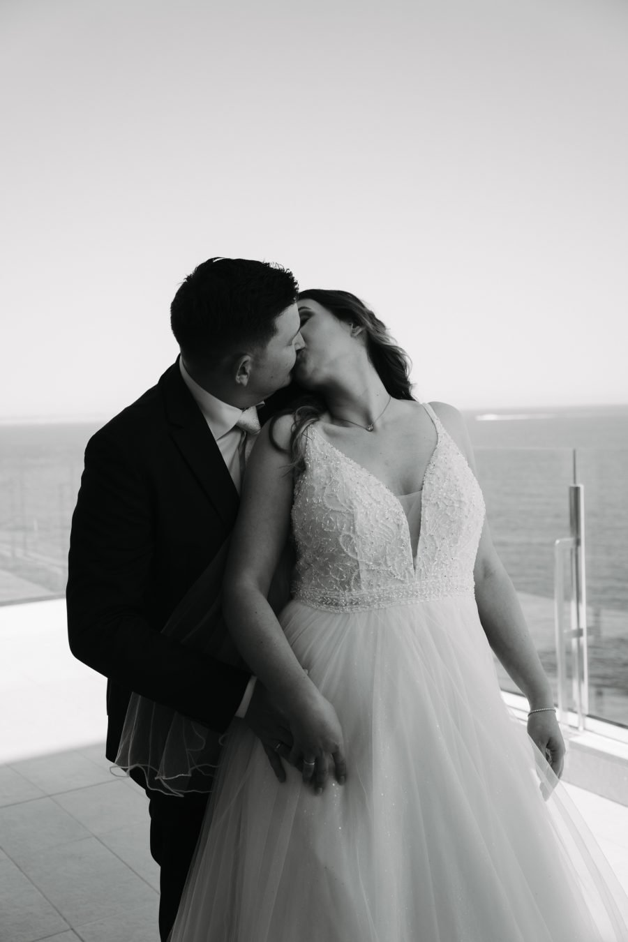 Brautpaar küsst sich vor dem Meer bei einer romantischen Hochzeit