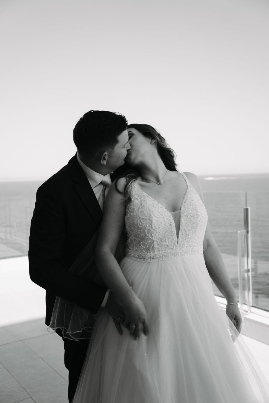 Brautpaar küsst sich vor dem Meer bei einer romantischen Hochzeit