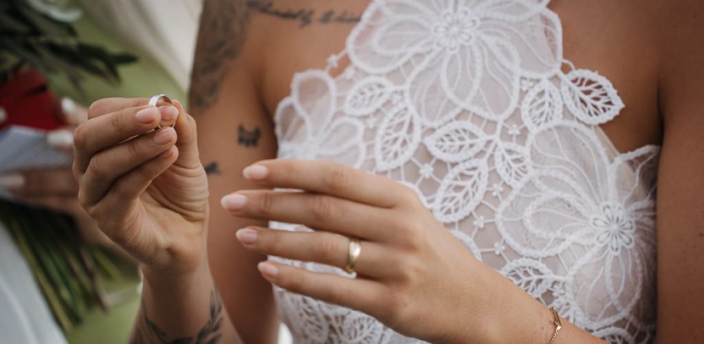 Detailaufnahme von Eheringen auf einem weißen Brautkleid